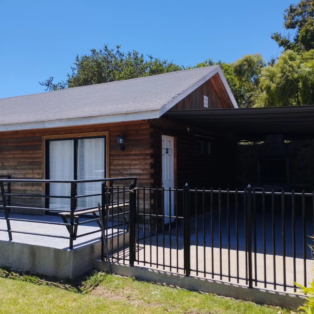 Cabaña 2 con reja negra y terraza de madera