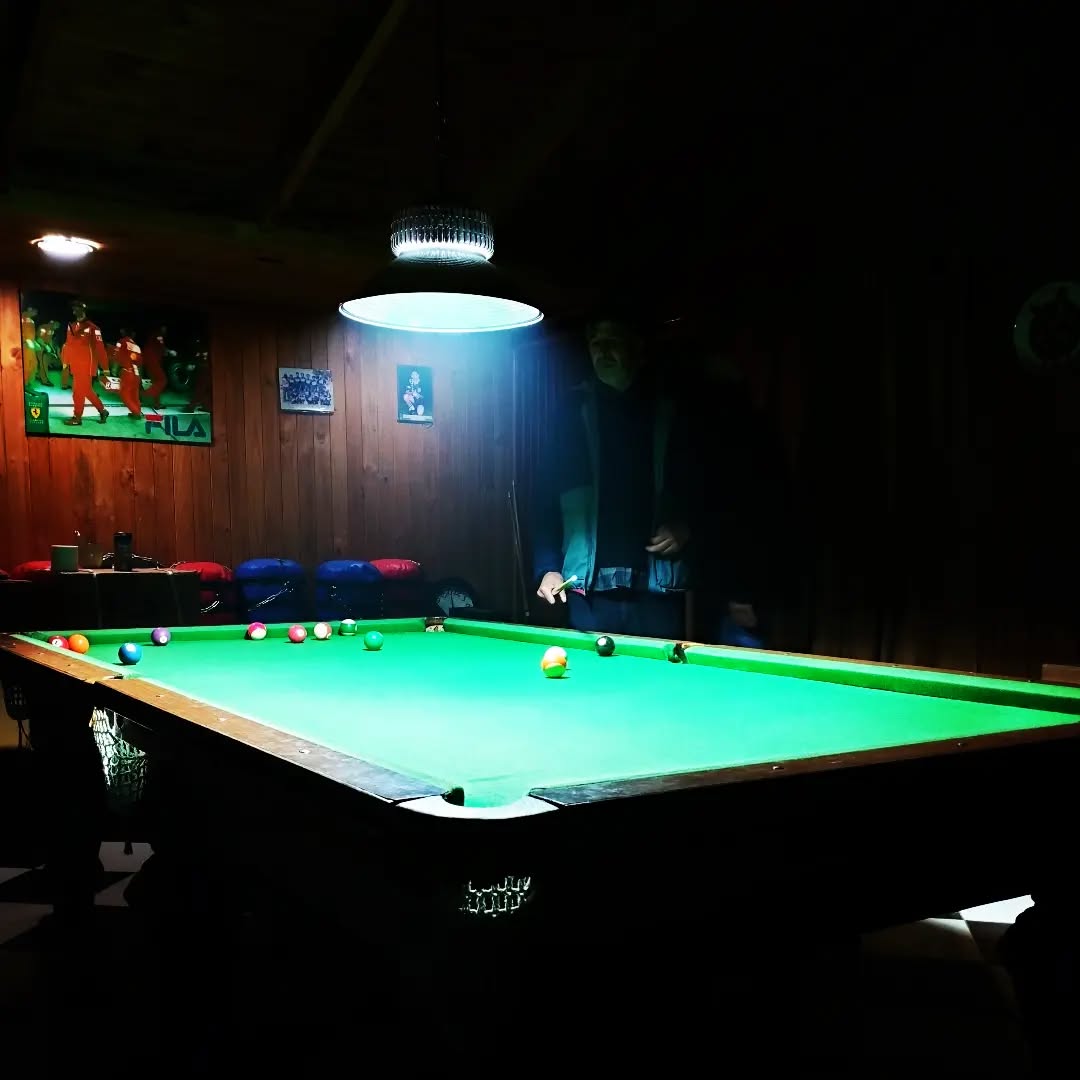 Salón de pool con mesa verde iluminada