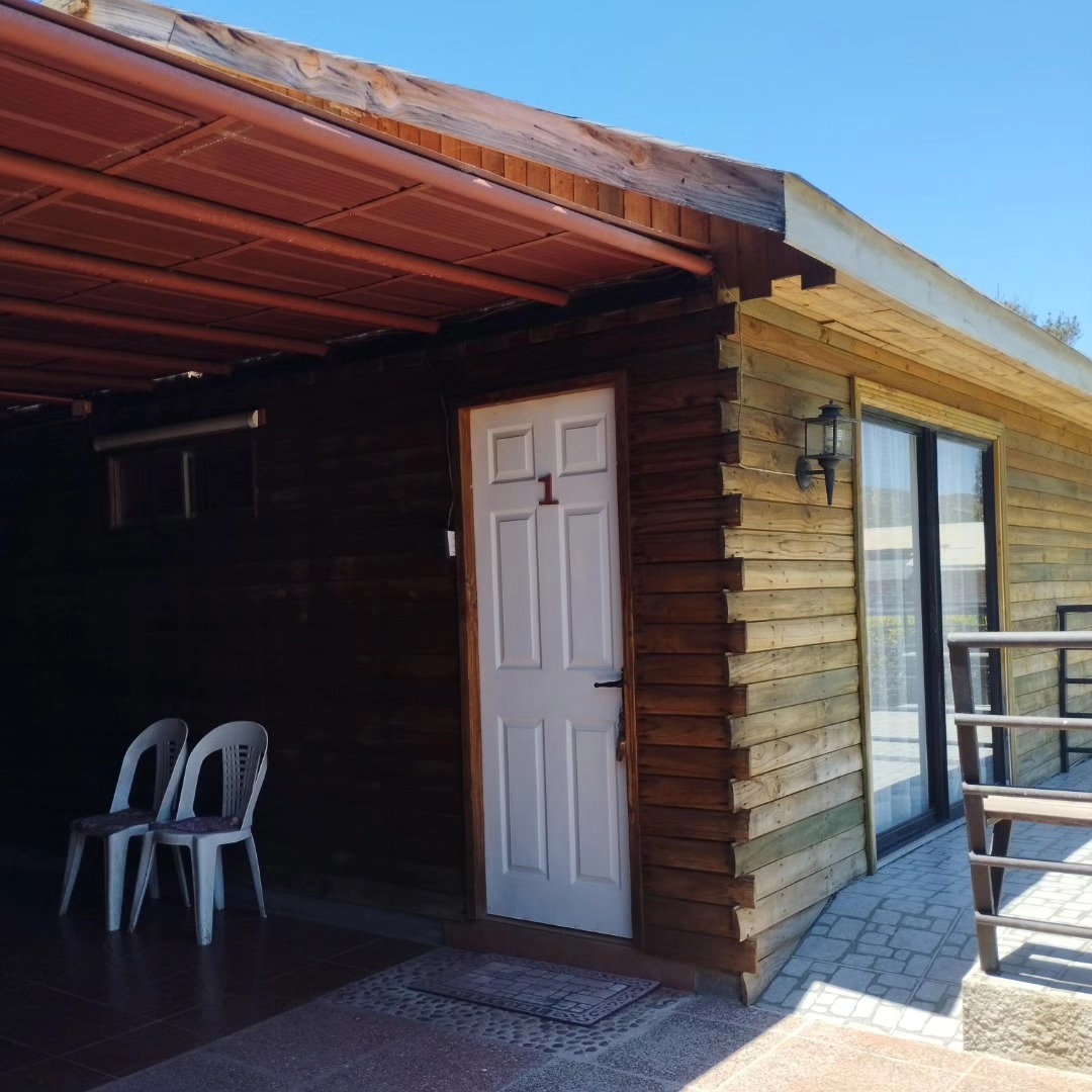 Cabaña 1 con terraza cubierta y sillas a la sombra